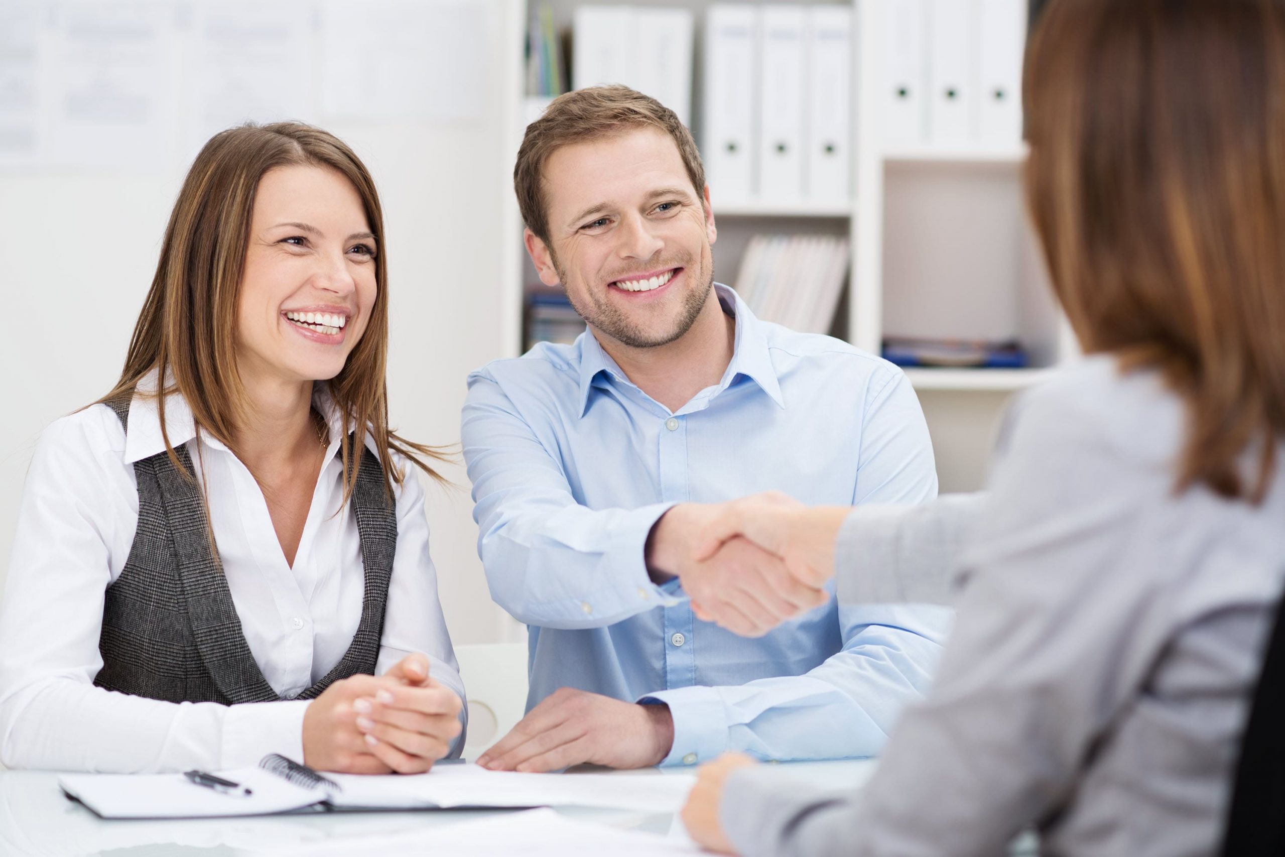 Business owners shaking hands after signing business package insurance documents with broker.