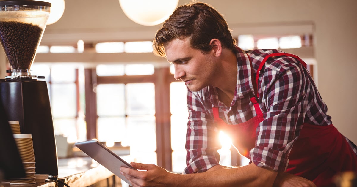 Cafe owner searching for hospitality insurance on tablet.