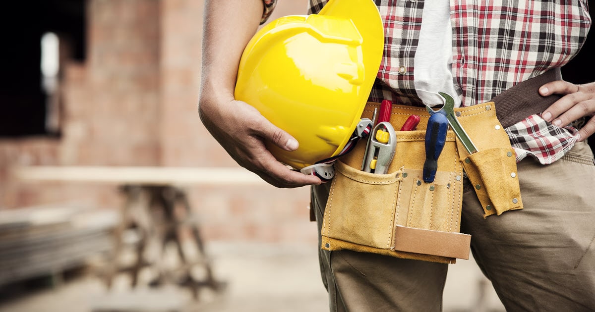 Man holding hard hat next to insured tool belt.